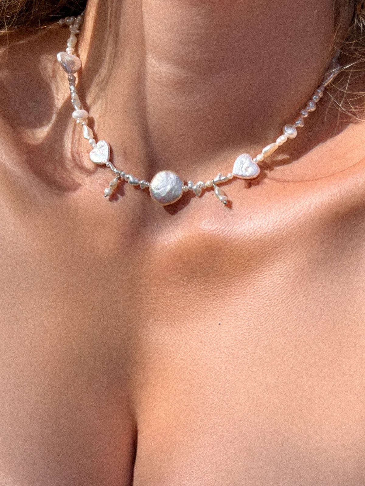 Handmade freshwater pearl necklace with baroque pearl centerpiece and heart-shaped pearls worn around the neck