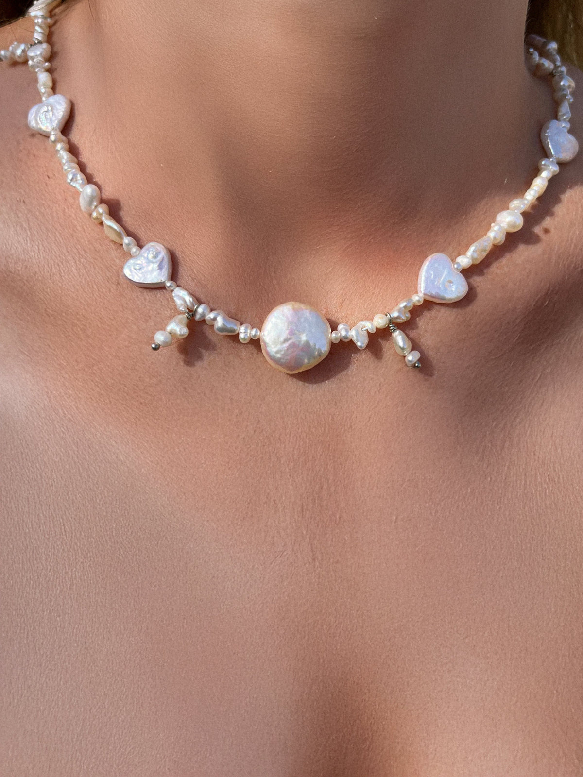 Handmade freshwater pearl necklace with baroque pearl centerpiece and heart-shaped pearls worn around the neck